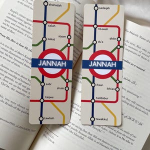 K&ouml;nnte beinhalten: Zwei rechteckige Lesezeichen mit U-Bahn-Kartendesign. Die Lesezeichen zeigen einen roten Kreis mit "JANNAH" in Wei&szlig;. Die Kartenlinien sind rot, blau, gelb und gr&uuml;n, mit arabischen W&ouml;rtern.