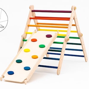 May include: A wooden climbing triangle with a slide attached. The triangle has rainbow colored rungs and the slide has colorful circles on it. The triangle has safety anchors on the bottom.