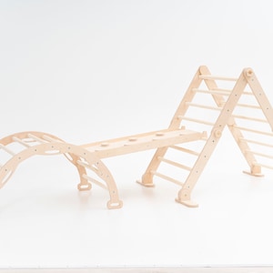 May include: A wooden climbing structure for children, featuring a ladder, a bridge, and a curved tunnel. The structure is made of natural wood and has a light brown color.