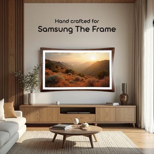 May include: A wooden frame with a curved edge surrounds a landscape photograph of a mountain range with a sunset in the background. The text "Hand crafted for Samsung The Frame" is displayed above the frame.