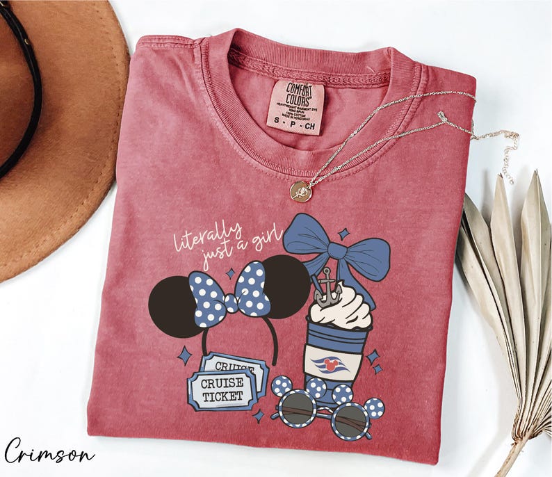 A red t-shirt with a graphic design of a cruise ticket, sunglasses, and a cup with a blue bow, along with a necklace and a hat.