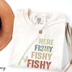 a hat, sunglasses, and a t - shirt with a fish on it