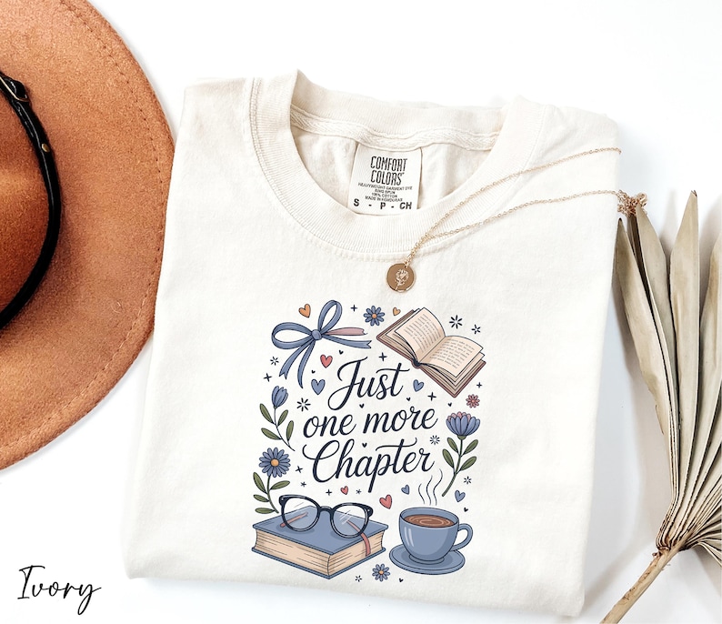 A white t-shirt with a printed design, a pair of glasses, a book, a cup of coffee, and a hat, along with a necklace and a plant, all arranged on a white background.