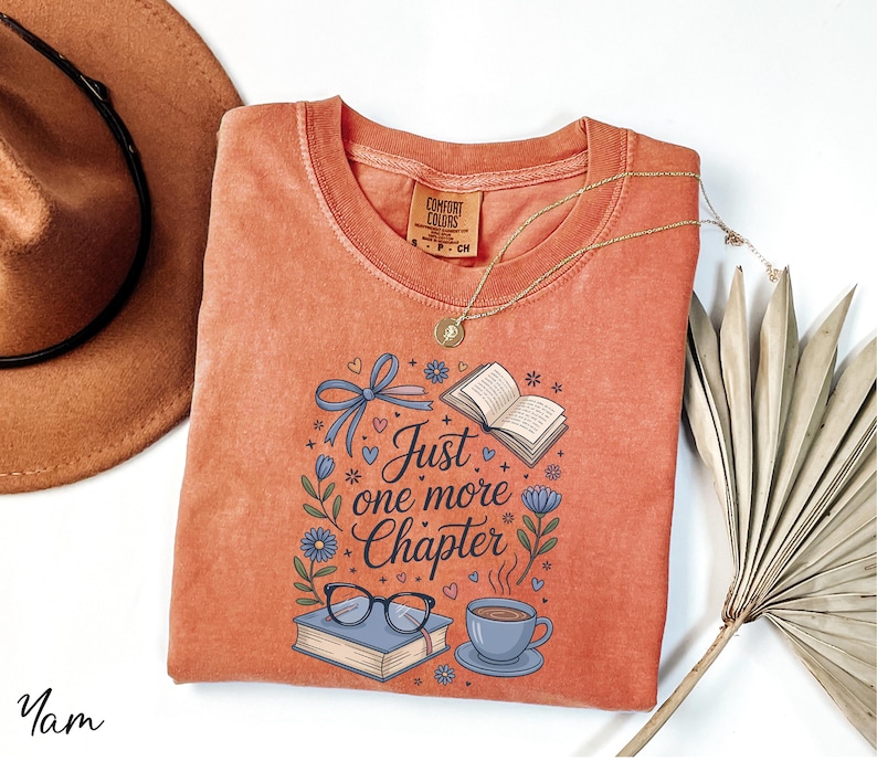 a red t-shirt with a printed design, a brown hat, a necklace, a fan, and some books, all arranged on a white background.