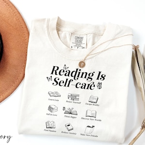 a hat, sunglasses, and t - shirt that says reading is self - care