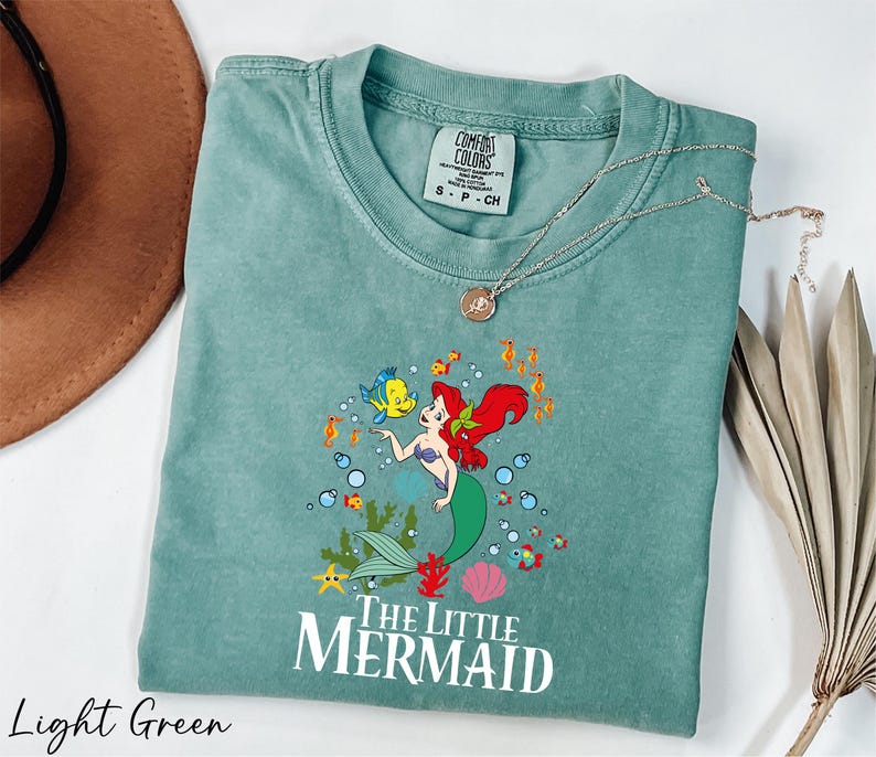 a green shirt with a little mermaid on it