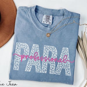 a blue t-shirt with the word "PARA" printed on it, along with a necklace and a hat.
