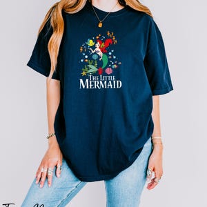 a woman wearing a blue t - shirt that says i'm a little mermaid