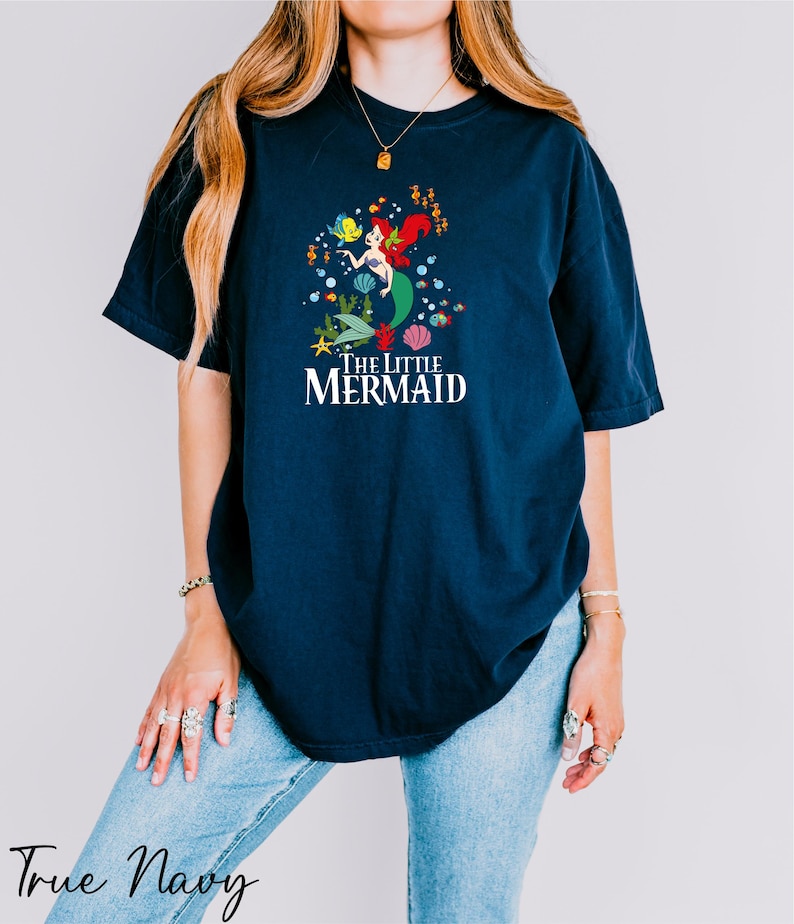 a woman wearing a blue t - shirt that says i'm a little mermaid