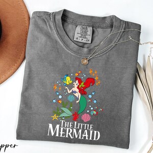 a gray shirt with a little mermaid on it