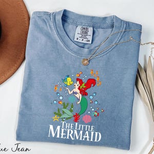 a blue shirt with a little mermaid on it