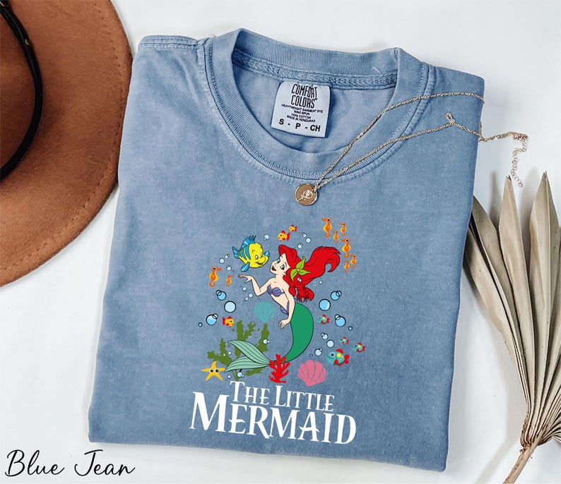 a blue shirt with a little mermaid on it