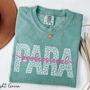 a light green t-shirt with the word "PARA" printed on it, along with a necklace and a hat.