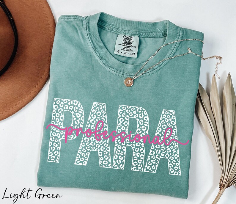a light green t-shirt with the word "PARA" printed on it, along with a necklace and a hat.