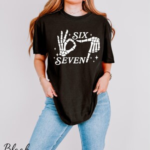A woman wearing a black t-shirt with a graphic design and text printed on it.