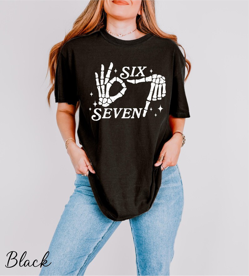 A woman wearing a black t-shirt with a graphic design and text printed on it.