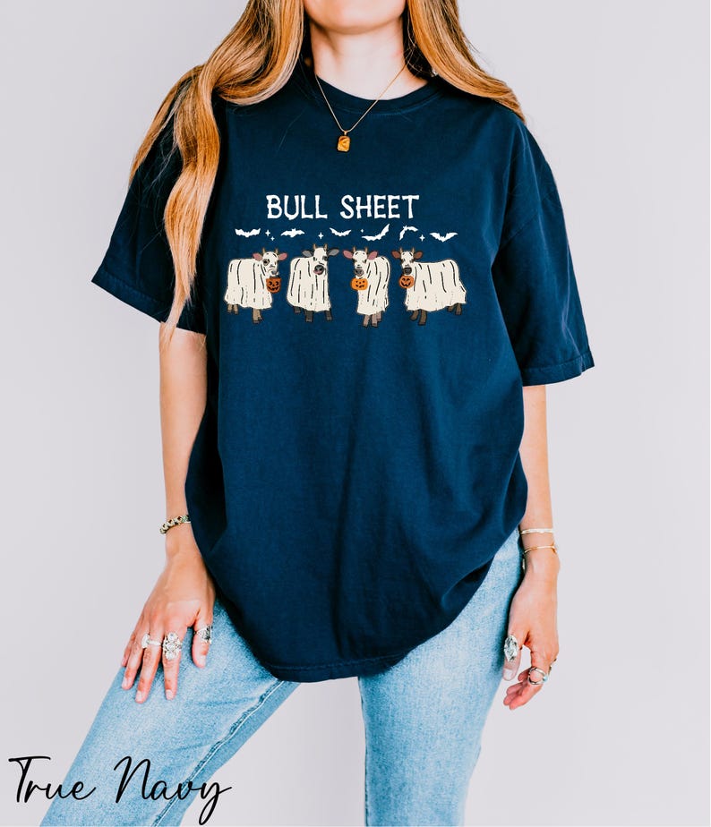 A woman wearing a navy blue t-shirt with a graphic design of three cows and the text "Bull Sheet" printed on it.