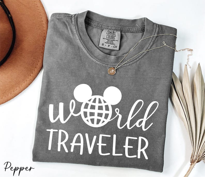 a t - shirt that says world traveler next to a hat