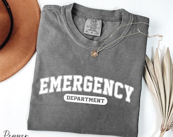May include: A gray t-shirt with the text "EMERGENCY DEPARTMENT" in white letters. The shirt is folded and has a distressed look.