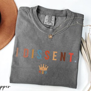 a t - shirt with the word disent on it next to a hat