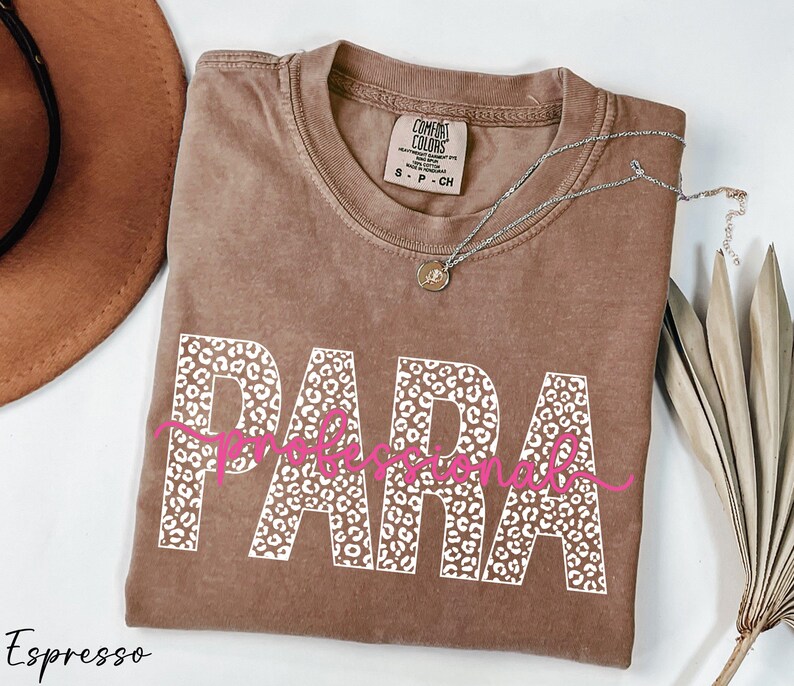 a brown t-shirt with the word "PARA" printed on it, along with a necklace and a hat.