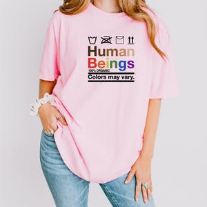 a woman wearing a pink shirt that says human beings