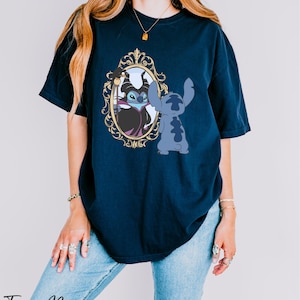 A woman wearing a navy blue t-shirt with a graphic of a character from the Disney movie "Stitch" and a mirror frame.