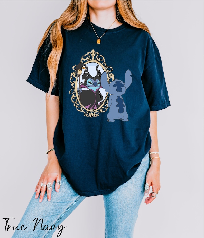 A woman wearing a navy blue t-shirt with a graphic of a character from the Disney movie "Stitch" and a mirror frame.