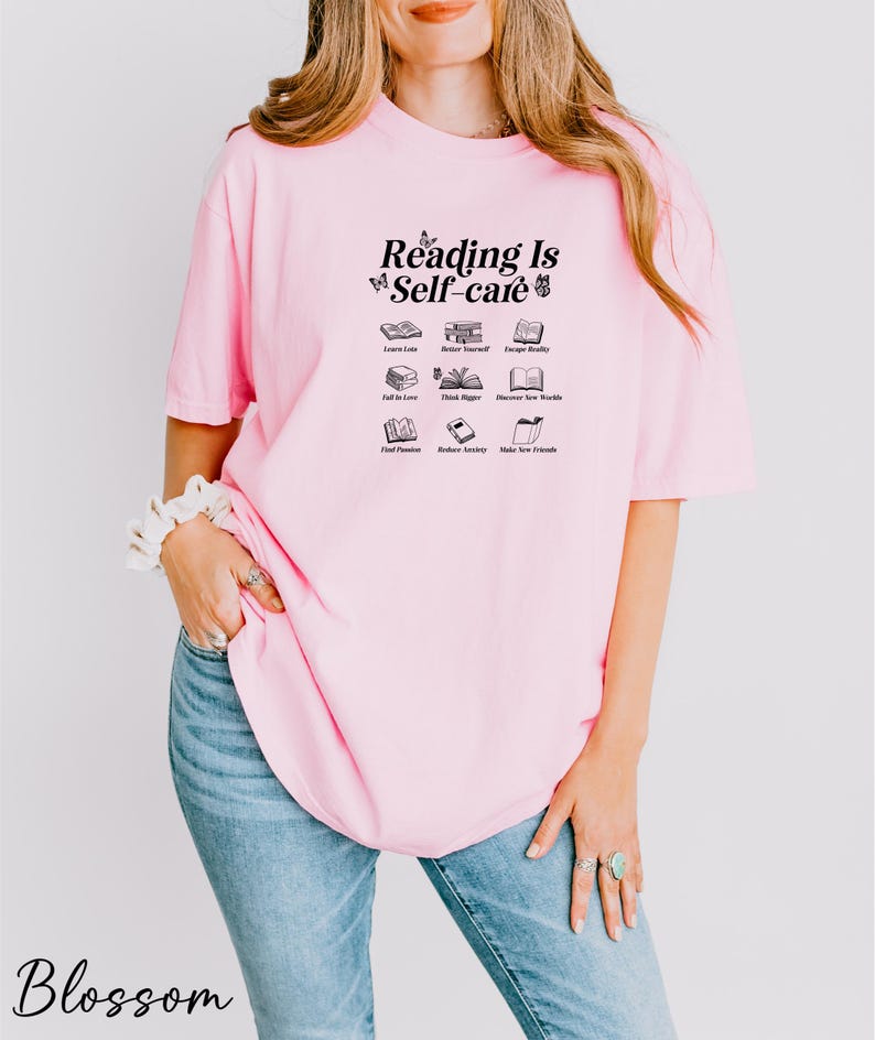a woman wearing a pink shirt that says reading is self care