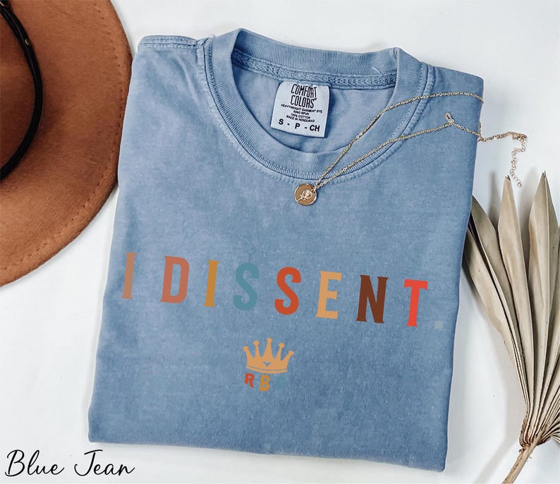 a t - shirt with the words dissent on it next to a hat
