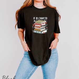 a woman wearing a black shirt with a stack of books on it