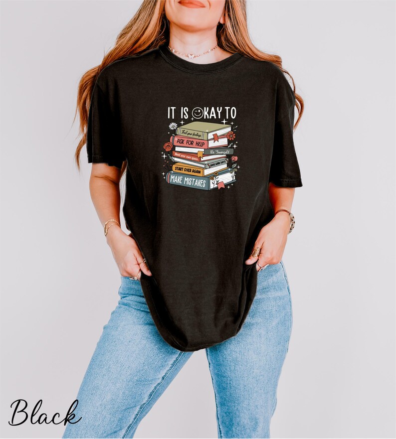 a woman wearing a black shirt with a stack of books on it
