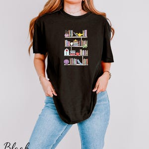 a woman wearing a black t - shirt with books on it