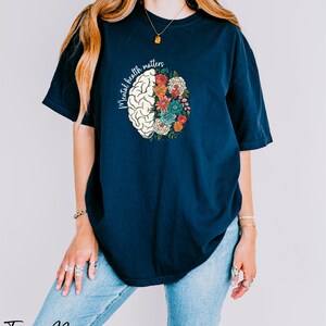a woman wearing a blue t - shirt with a flowered brain on it