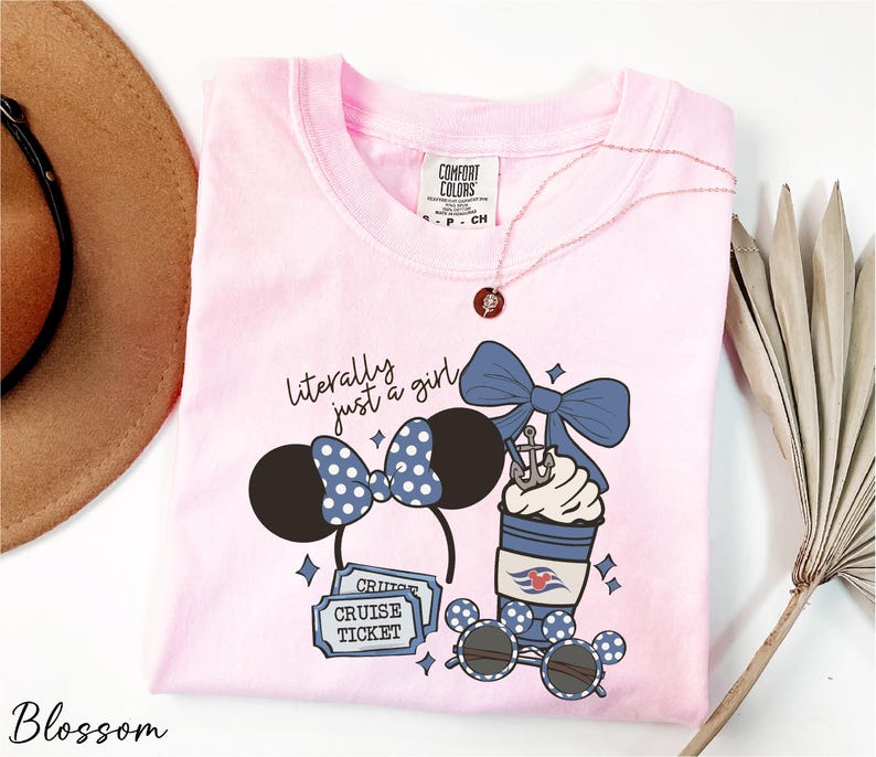 A pink t-shirt with a graphic design featuring a pair of Minnie Mouse ears, a cup of ice cream, sunglasses, and a cruise ticket, along with the text "Literally just a girl" and "Cruise Ticket".