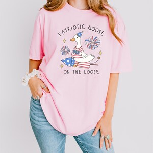 a woman wearing a pink patriotic goose t - shirt