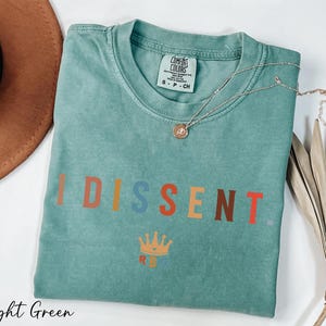 a t - shirt with the word disent on it next to a hat