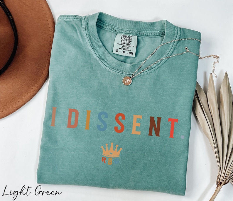 a t - shirt with the word disent on it next to a hat