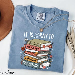 a blue tshirt with a stack of books on it