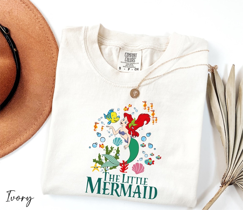 a hat, sunglasses, and t - shirt with the little mermaid on it