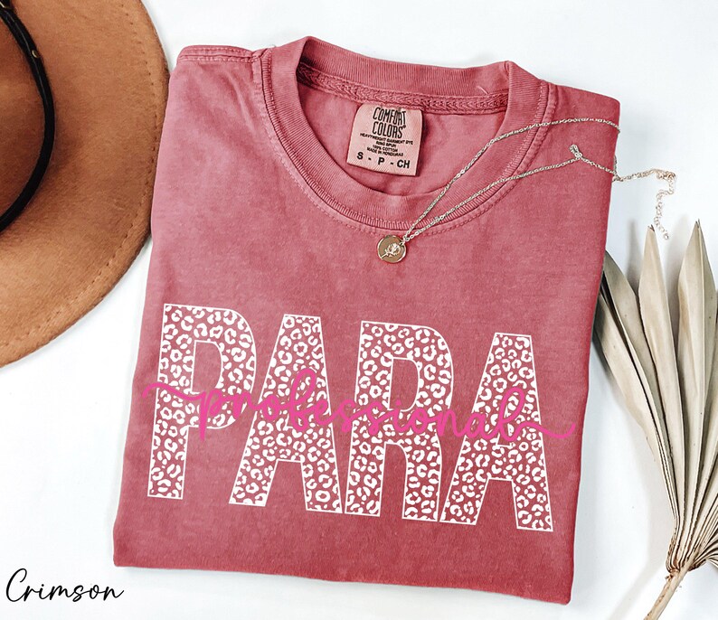 a pink t-shirt with the word "PARA" printed on it, along with a necklace and a hat.