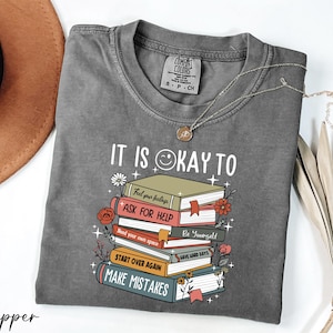 a gray shirt with a stack of books on it