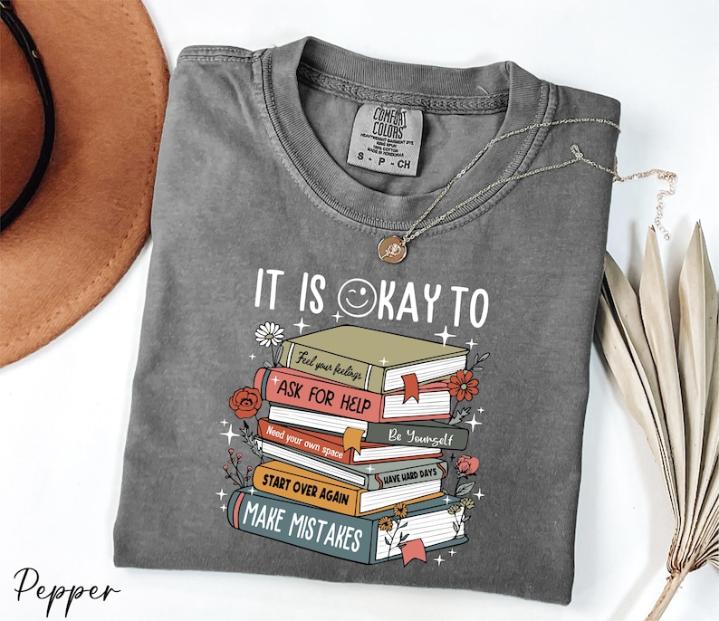 a gray shirt with a stack of books on it