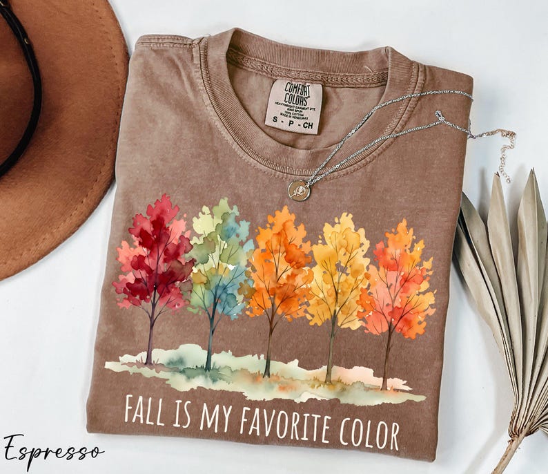 a brown t-shirt with a colorful autumn tree design and the text "FALL IS MY FAVORITE COLOR" printed on it.