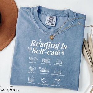 a blue t - shirt that reads reading is self - care