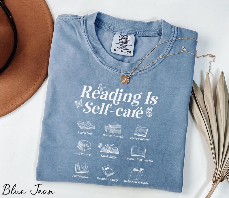 a blue t - shirt that reads reading is self - care