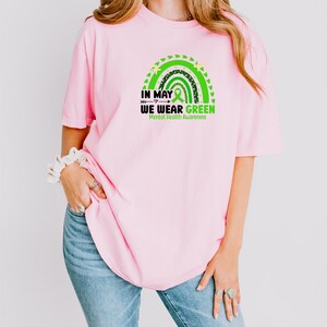 a woman wearing a pink shirt that says in may we wear green