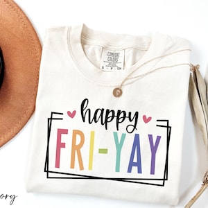 May include: Ivory t-shirt with a black graphic that says "happy" with a pink heart and "FRI-YAY" in rainbow colors.