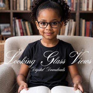 Pode incluir: Uma criança de cabelo encaracolado usa óculos de armação preta e uma t-shirt preta lisa, segurando um livro aberto. A imagem apresenta uma sobreposição de texto branco que diz Looking Glass Views Digital Downloads em fonte cursiva e serifada.