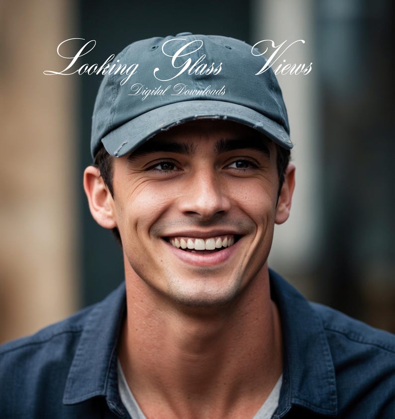May include: A man with a friendly smile is wearing a gray baseball cap with the text "Looking Glass Views Digital Downloads" on the front. He is wearing a dark blue shirt.